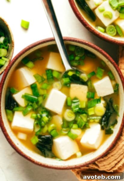 Close-up of a serving of miso soup in a bowl with a focus on fresh ingredients.
