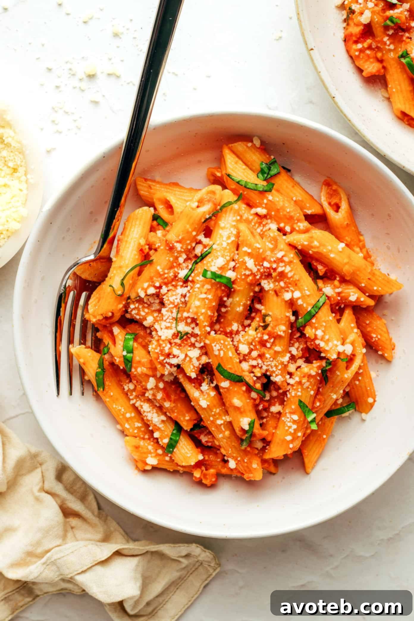 Velvety Vodka Cream Penne 8 A serving of Penne Alla Vodka in a bowl, garnished with fresh basil and Parmesan cheese.