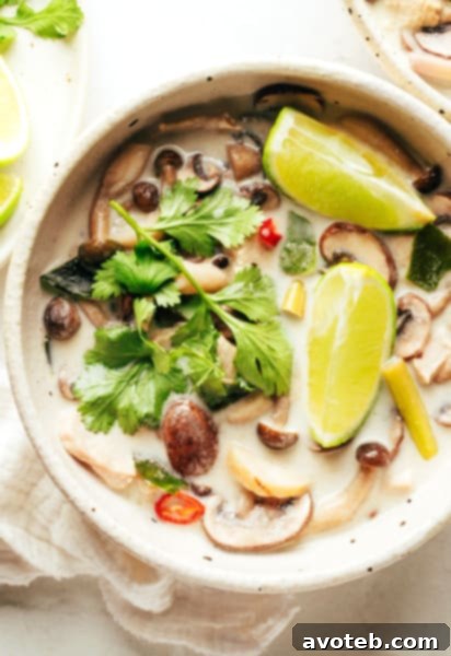 Tom Kha Gai in a bowl with limes and cilantro