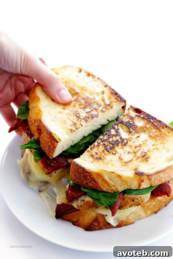 The ultimate cheese pull shot of a Chicken Florentine Grilled Cheese sandwich.