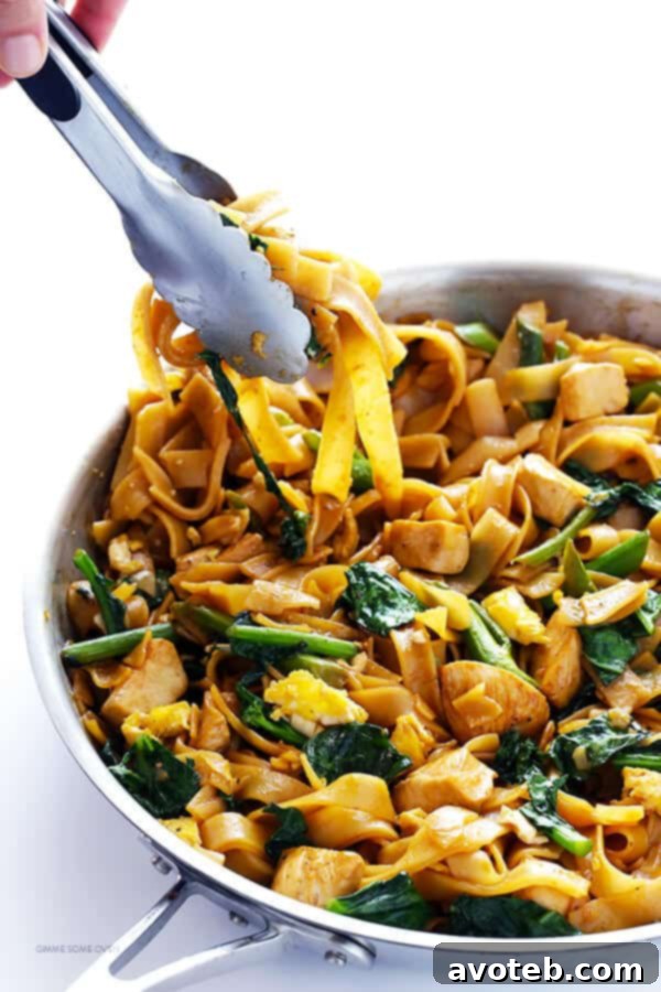 Cooking Pad See Ew: Stir-frying the wide rice noodles with Chinese broccoli, chicken, and sauce in a hot pan.