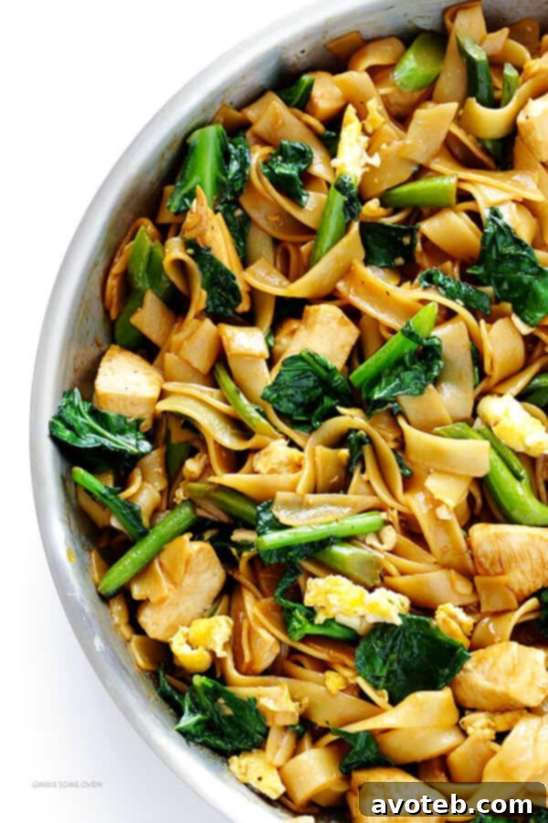 Overhead shot of a full plate of Pad See Ew with a fork, ready to eat.