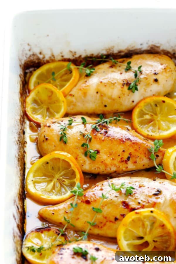 Plated baked lemon chicken with lemon wedges and thyme