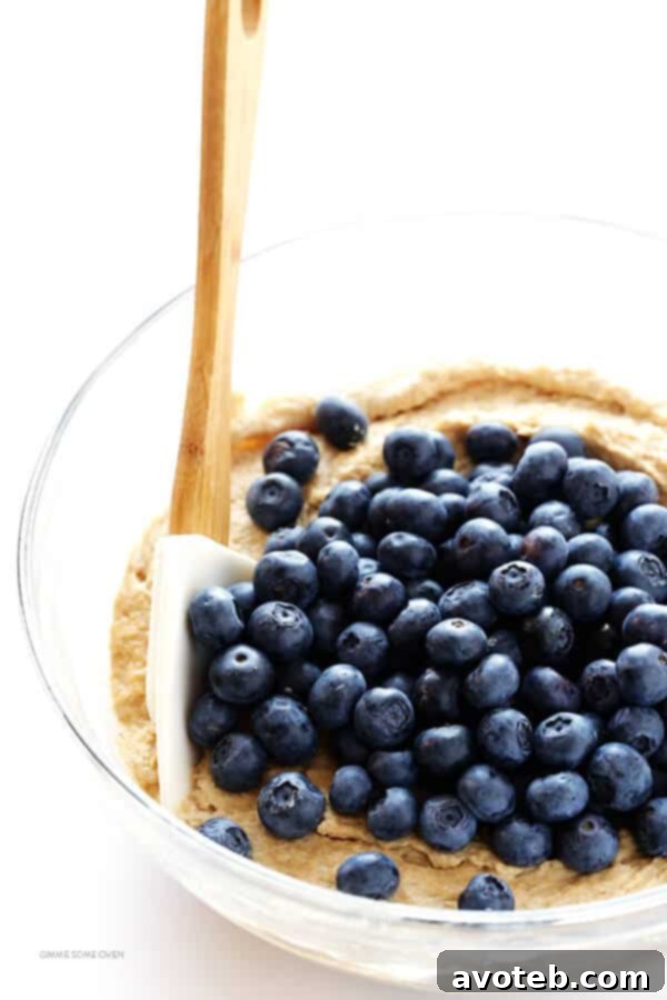 Freshly baked Healthier Blueberry Muffins arranged on a cooling rack, showcasing their rustic charm and golden tops. | gimmesomeoven.com