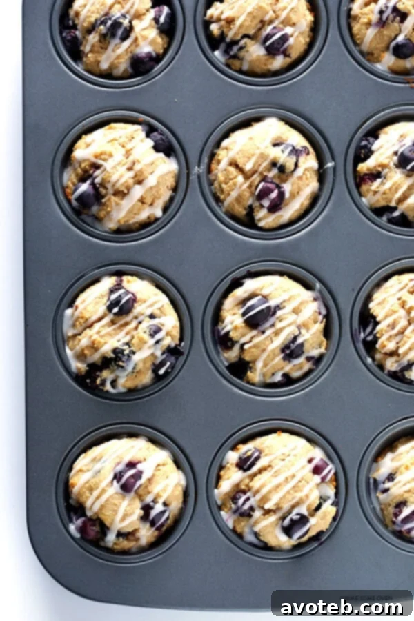 A close-up shot of freshly glazed Healthier Blueberry Muffins, showing the delicate drizzle over their golden tops. | gimmesomeoven.com