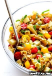 Vibrant Caprese Pasta Salad with cherry tomatoes, mozzarella pearls, and fresh basil, drizzled with balsamic dressing.