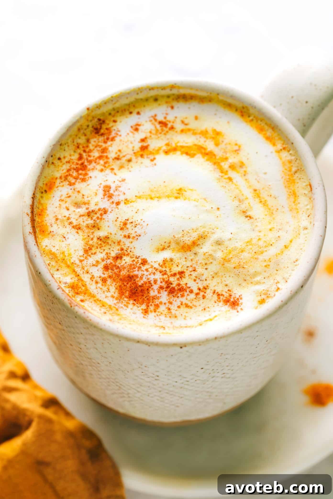 A hand whisking spices into warm milk for golden milk preparation.