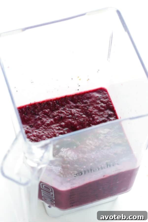 Ingredients for blueberry kale smoothie in a blender: kale, blueberries, banana, chia seeds, ginger, and almond milk.