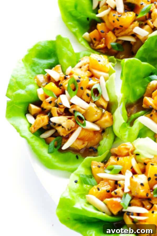 Plated Orange Chicken Lettuce Wraps garnished with almonds, sesame seeds, and green onions, ready to be enjoyed.