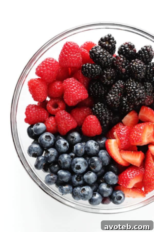 A vibrant mix of fresh summer berries, including strawberries, blueberries, raspberries, and blackberries, ready for the crisp.