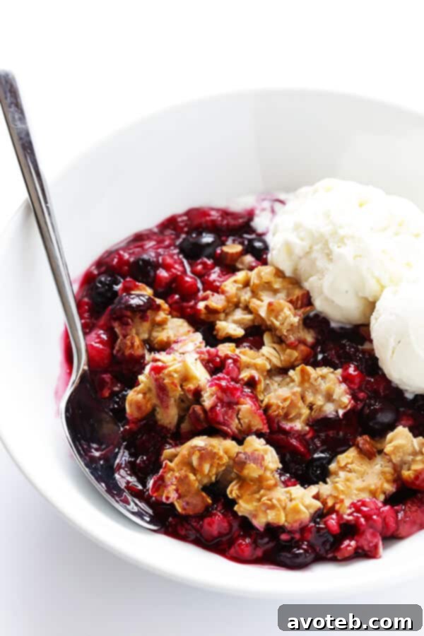 A serving of warm Berry Almond Crisp topped with melting vanilla ice cream.