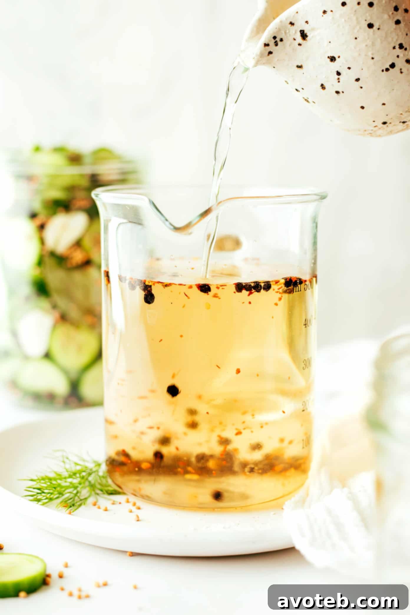 A close-up of a jar filled with layered cucumbers, dill, and garlic.