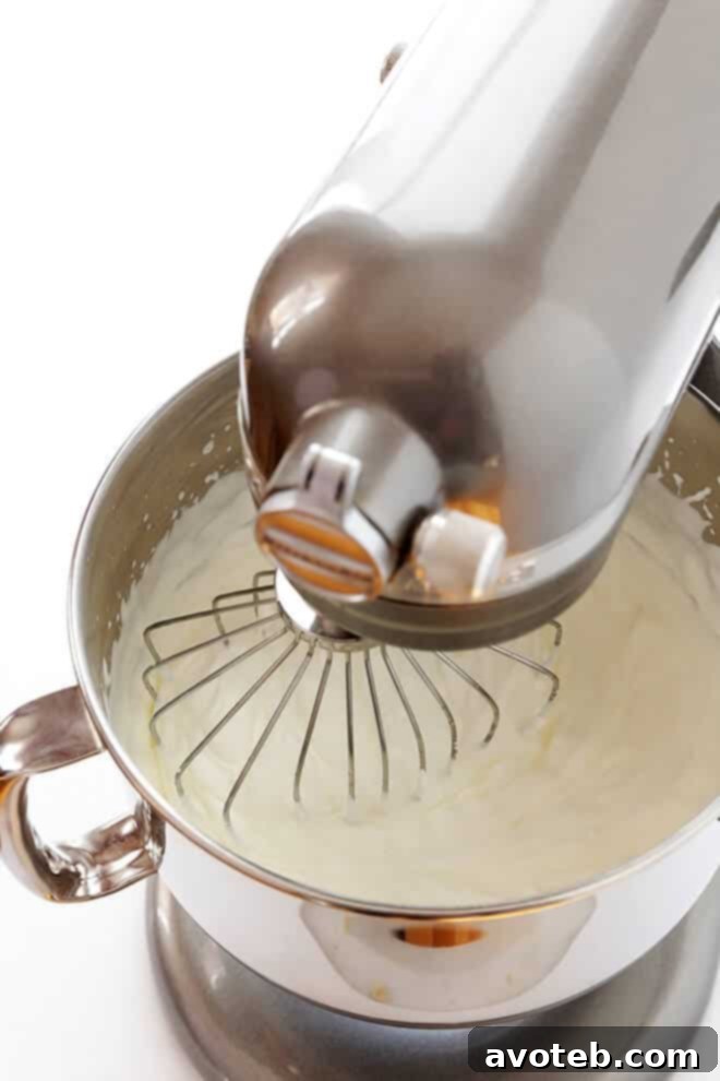 Whipping process for Homemade Whipped Cream: Cream being whipped in a bowl with an electric mixer, forming soft peaks.