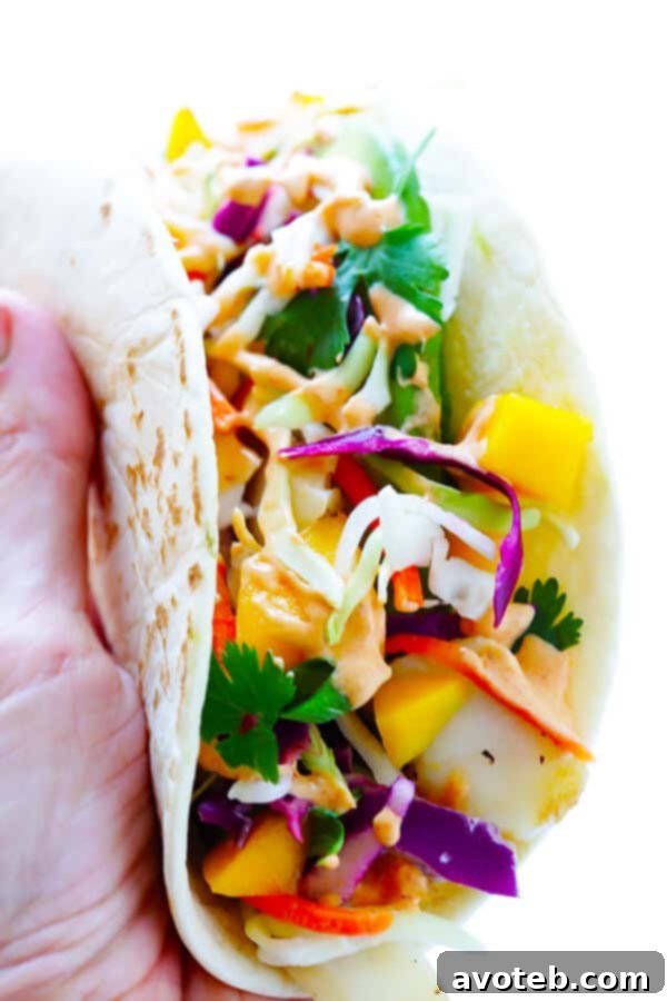 This Mango Chipotle Fish Tacos recipe is made with flaky mild fish, filled with a zesty mango slaw, and drizzled with a creamy chipotle lime sauce. So easy to make, and ready to go in less than 30 minutes! | gimmesomeoven.com