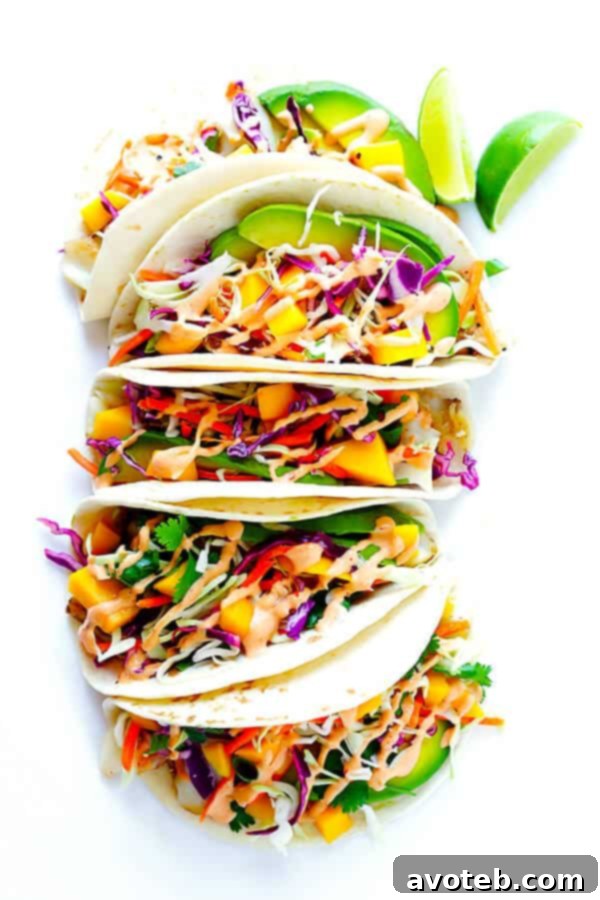 This Mango Chipotle Fish Tacos recipe is made with flaky mild fish, filled with a zesty mango slaw, and drizzled with a creamy chipotle lime sauce. So easy to make, and ready to go in less than 30 minutes! | gimmesomeoven.com