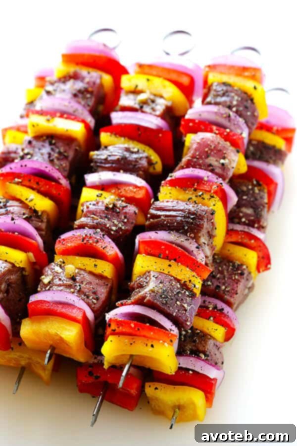 Marinated flank steak pieces waiting to be threaded onto skewers with vegetables.