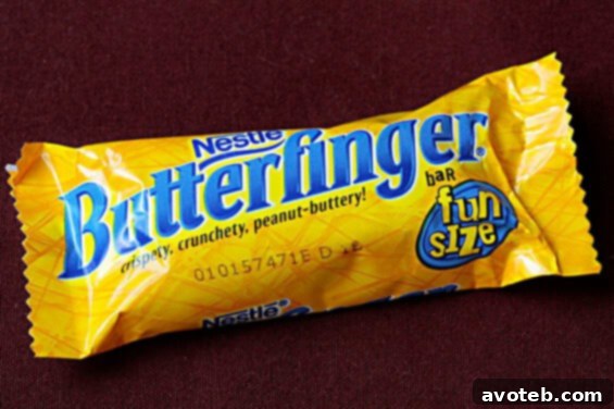 Close-up of creamy Butterfinger ice cream in a white bowl, showing candy chunks.