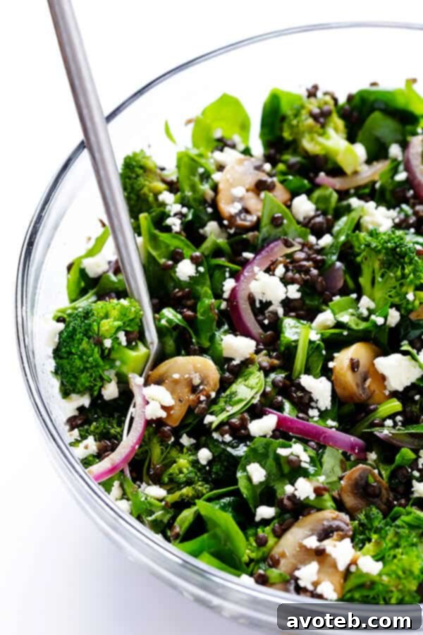 Invigorating Lentil & Spinach Medley 8 Close-up of the Zesty Lentil Spinach Salad being tossed in a large bowl, ensuring all ingredients are evenly coated with the tangy lemon dressing.