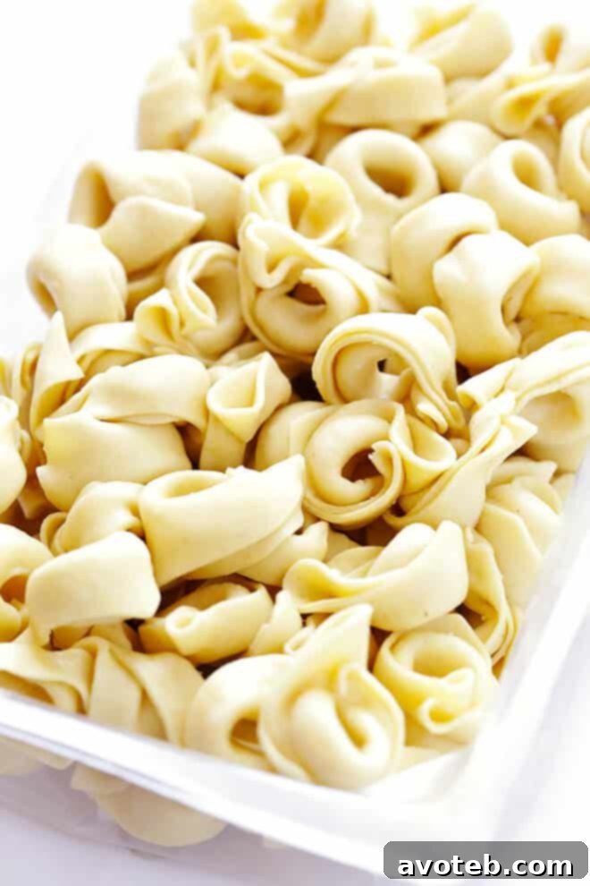 Velvety Italian Sausage Tortellini Soup 4 Ingredients for Creamy Tortellini Soup with Italian Sausage laid out, including a package of tortellini, fresh spinach, carrots, onions, and ground Italian sausage. Emphasis on fresh, quality ingredients for the best flavor.