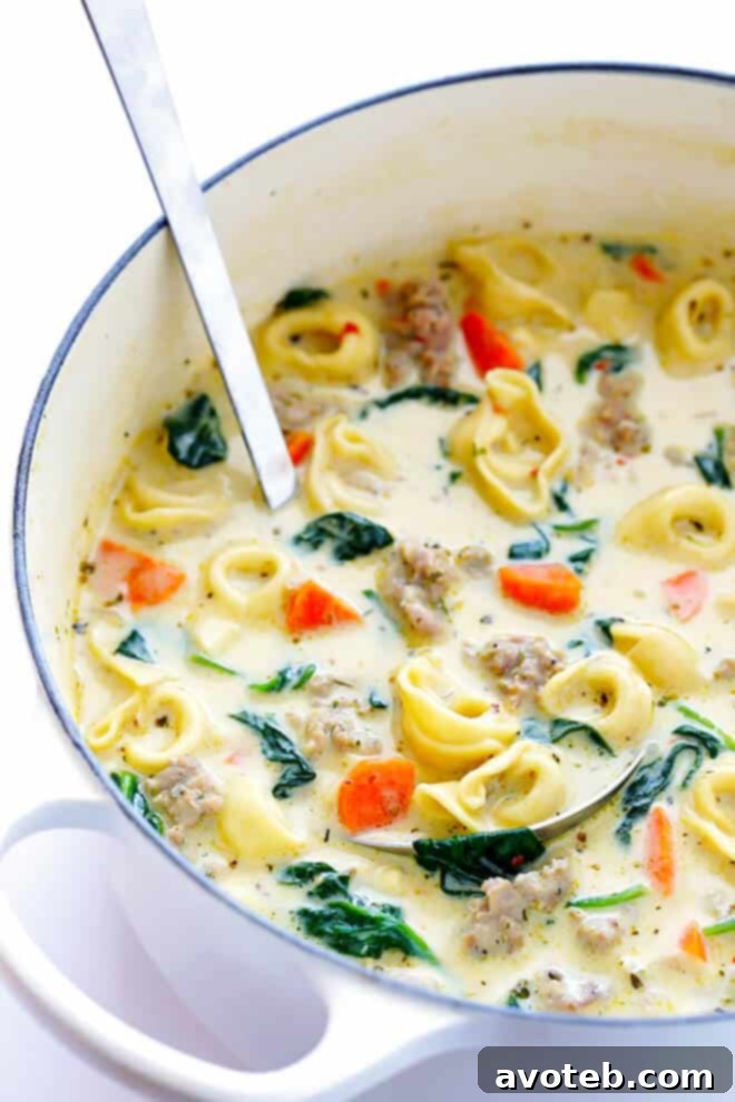 Velvety Italian Sausage Tortellini Soup 7 A large pot of Creamy Tortellini Soup with Italian Sausage simmering on the stove, filled with cheesy tortellini, browned sausage, and fresh green vegetables, emitting steam and a comforting aroma.