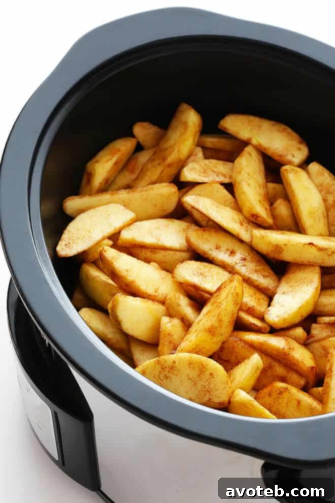Preparing the apple mixture for Slow Cooker Apple Crisp in a large mixing bowl.