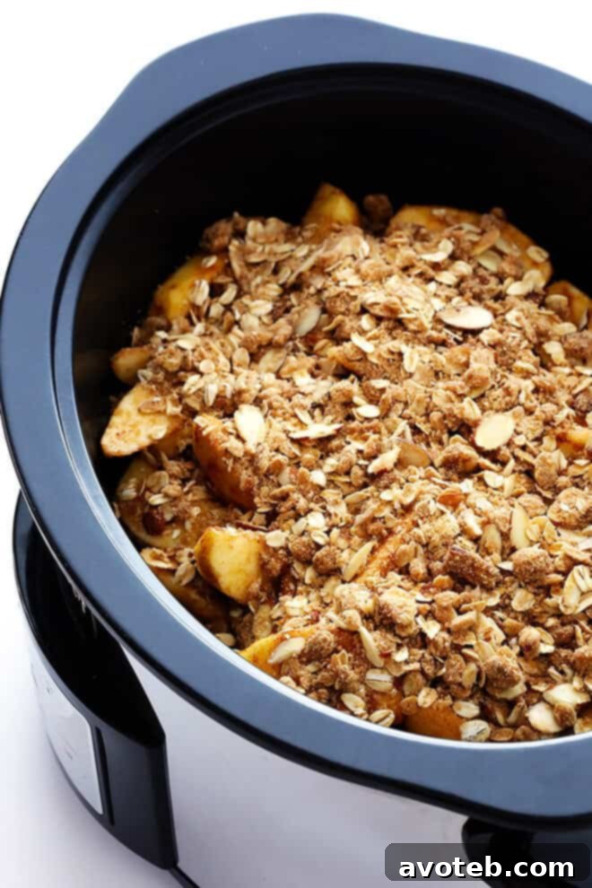 Spreading apples in a slow cooker for a homemade Apple Crisp recipe.