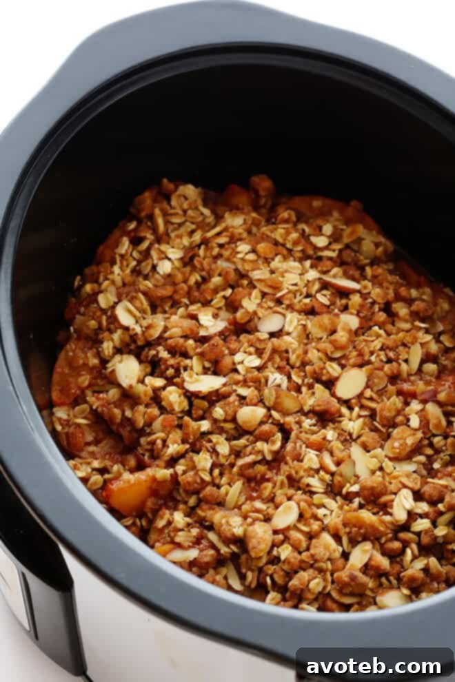 Slow Cooker Apple Crisp cooking with a kitchen towel under the lid to keep the topping crispy.