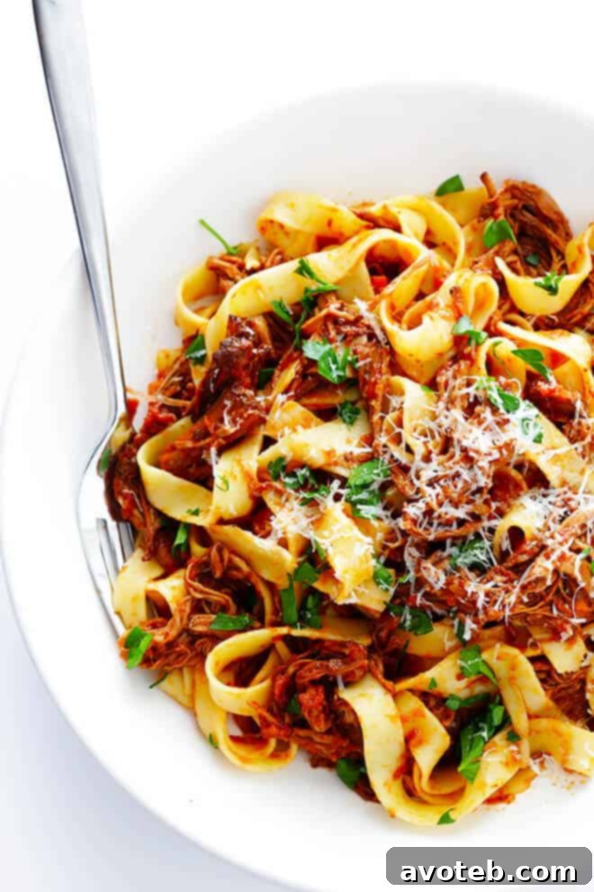 A serving of Slow Cooker Beef Ragu generously spooned over pappardelle pasta, ready to be garnished.