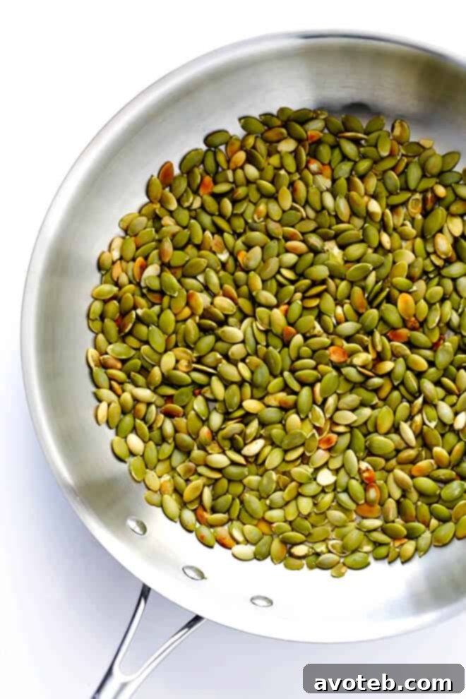 Close-up of toasted pumpkin seeds, a key ingredient in authentic Pepián sauce, prepared in a skillet.