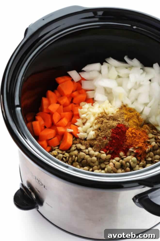 Close-up of Slow Cooker Curried Lentil Soup simmering in a crock-pot, showcasing the rich texture of lentils, carrots, and onions – a healthy and easy-to-make vegetarian dish. | gimmesomeoven.com