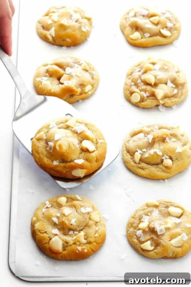 Several Salted White Chocolate Macadamia Nut Cookies arranged on a cooling rack, highlighting their golden brown edges and delicious toppings.