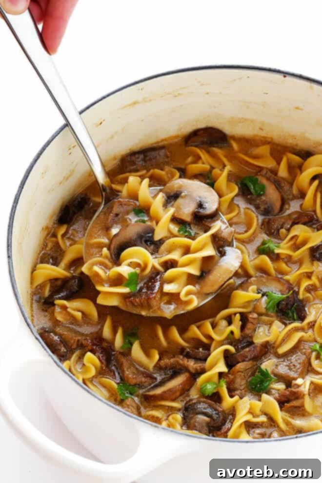 Simmering beef stock, Worcestershire, and egg noodles for Stroganoff Soup