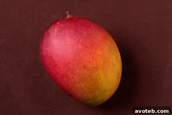 Close-up view of a mango being cut on a wooden board, showing the process of slicing around the pit.