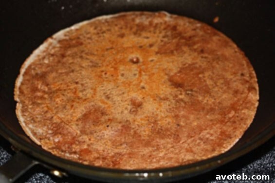 A serving of chocolate banana crepes topped with whipped cream, chocolate syrup, and fresh banana slices, ready to eat.
