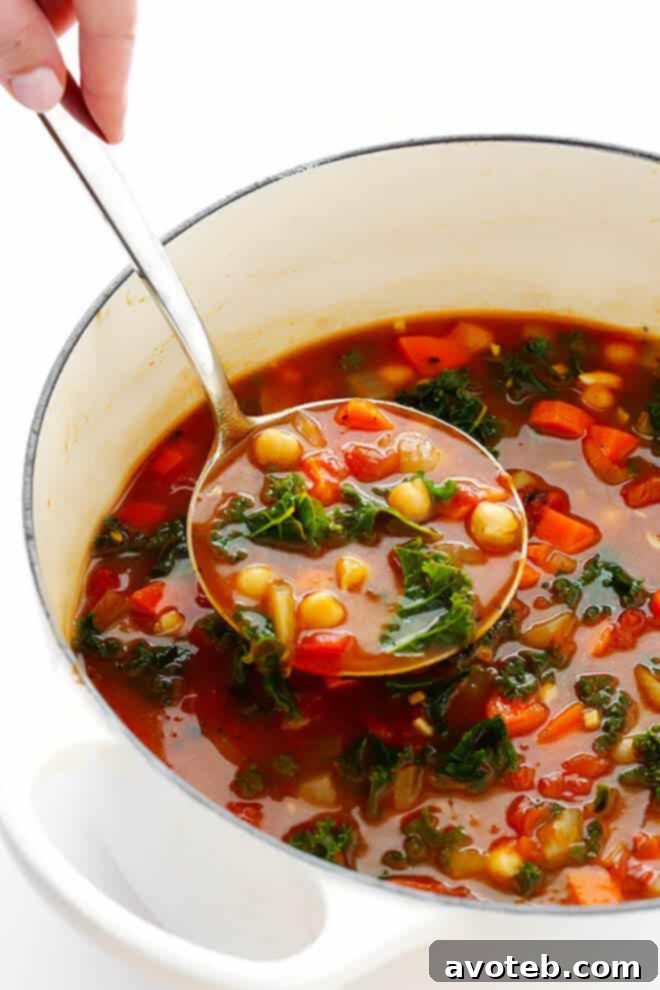 Fresh kale being gently stirred into the vibrant Moroccan Chickpea Soup