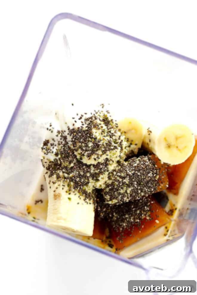 All ingredients for a Coffee Protein Smoothie laid out: coffee ice cubes, banana, almond milk, Greek yogurt, chia, and hemp seeds