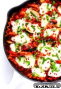 A Skillet Veggie Lasagna in a cast iron pan, topped with melted mozzarella and fresh basil.