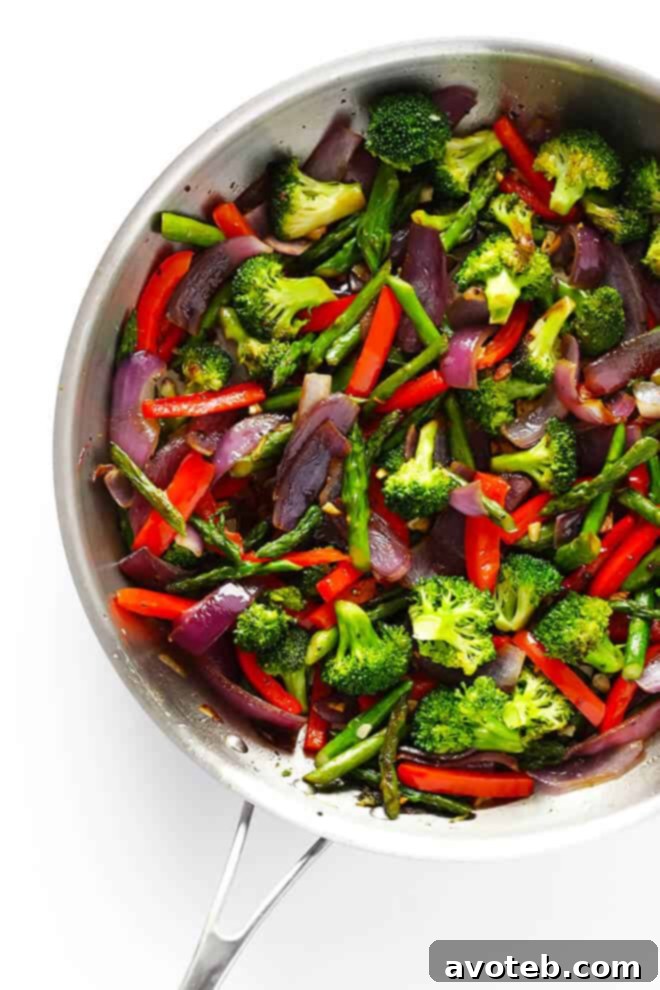 A vibrant mix of fresh vegetables like asparagus, broccoli, and red bell peppers sautéing in a pan, releasing their delicious aromas.