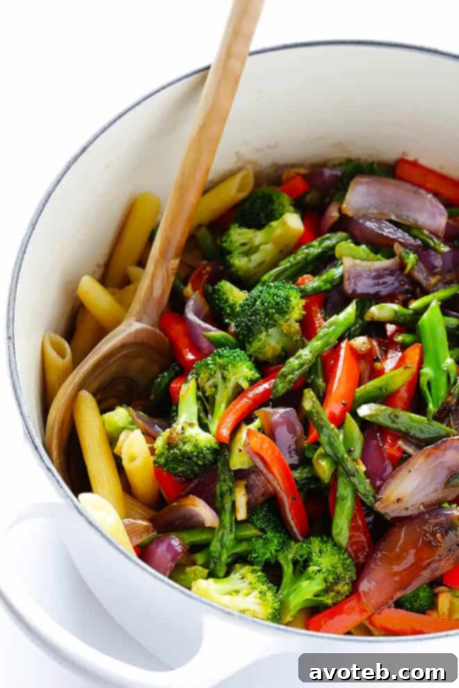 Cooked penne pasta being tossed with balsamic vinegar and olive oil in a stockpot, preparing for the final sauté with vegetables.