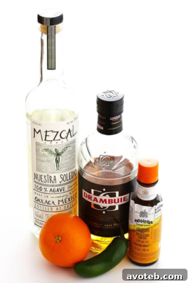 Close-up of the Oaxacan Rusty Nail cocktail, showing the orange peel and jalapeño slice in the glass, highlighting its fresh and spicy elements.