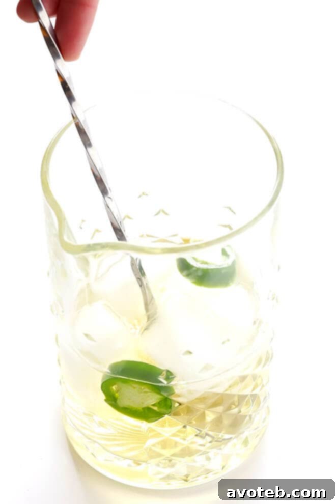 Ingredients for the Oaxacan Rusty Nail laid out: mezcal, Drambuie, orange bitters, jalapeño, and an orange for garnish, emphasizing its simple yet refined components.