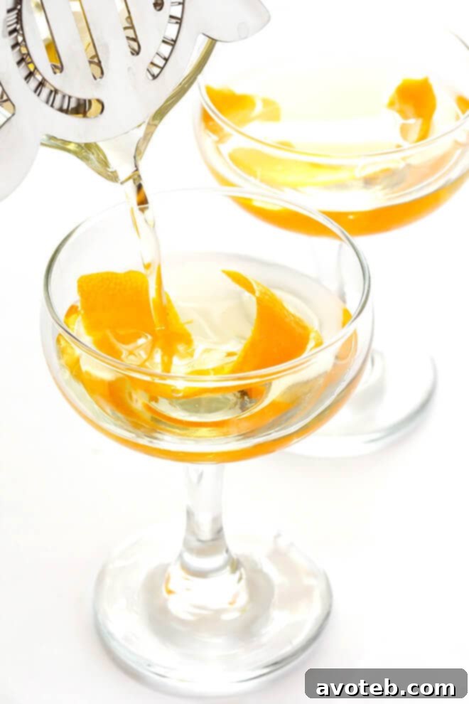 A hand stirring the Oaxacan Rusty Nail cocktail in a shaker, indicating the mixing process for optimal flavor integration and chill.