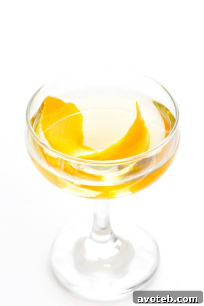The finished Oaxacan Rusty Nail cocktail served in a rocks glass with ice, garnished with an orange peel and jalapeño, ready to be enjoyed.