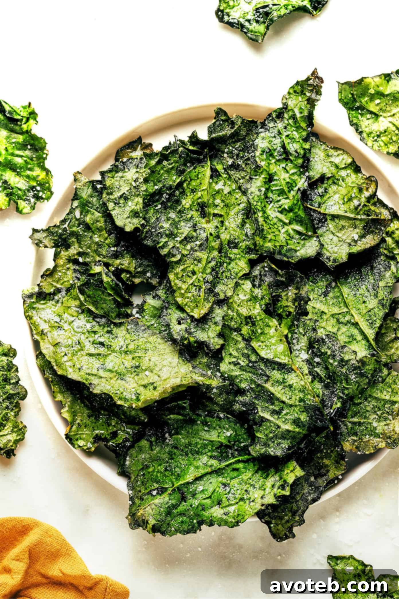Freshly baked crispy kale chips cooling on a parchment-lined baking sheet.