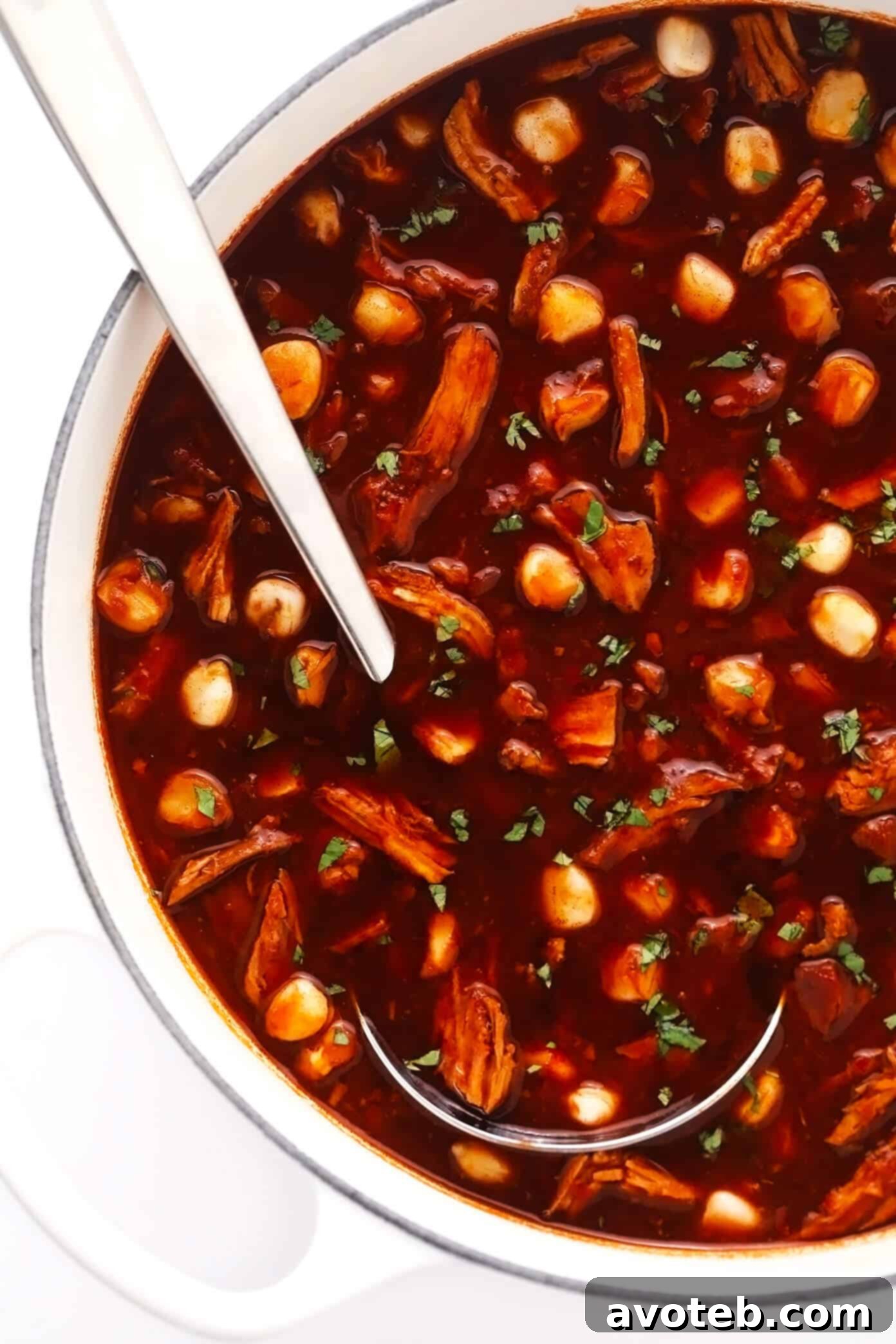 Simmering Pot of Pozole Rojo A large pot of simmering pork pozole rojo, bubbling gently on the stovetop, showcasing the rich red broth and tender ingredients before serving.