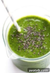 A vibrant green Matcha Ginger Green Smoothie in a glass, with a straw and garnishes.