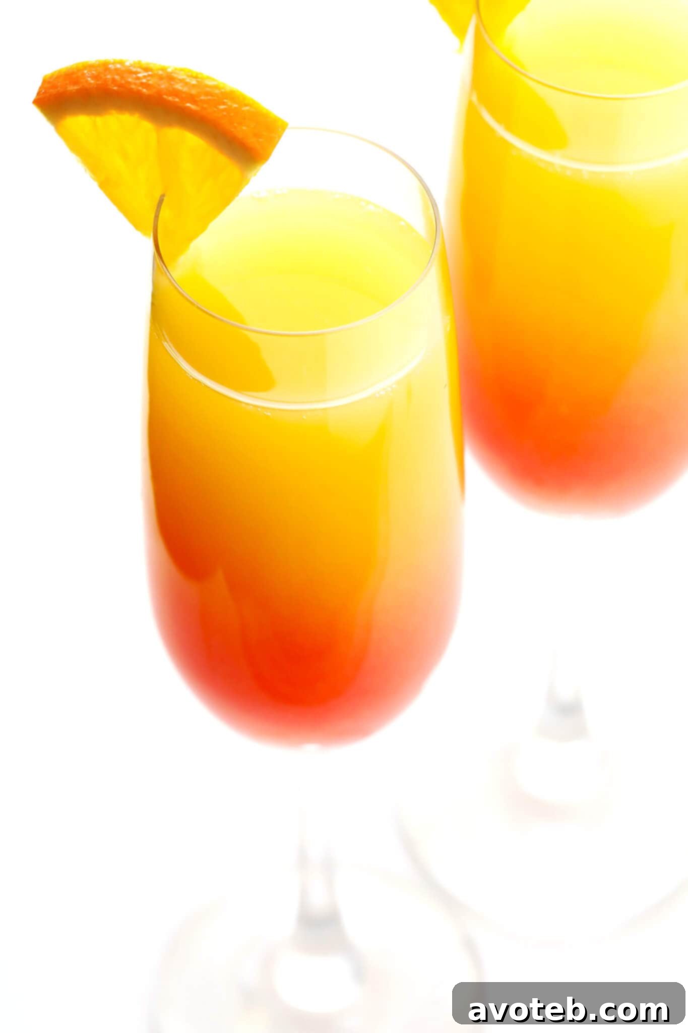 Agave Sunrise Mimosa 6 A close-up shot of a perfectly layered Tequila Sunrise Mimosa in a champagne flute, garnished with an orange slice.