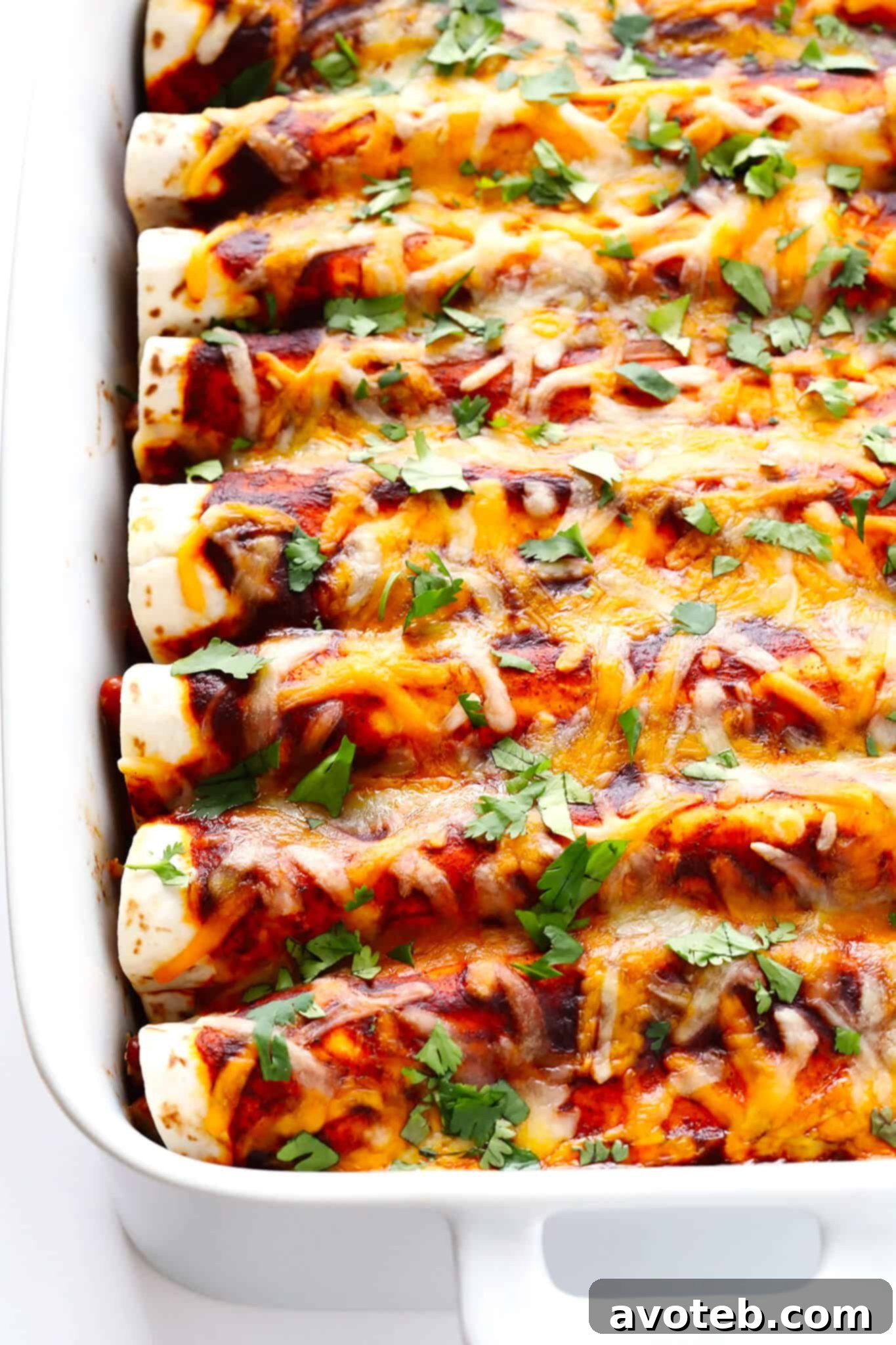 Close-up of baked Ancho Chicken Enchiladas, showing melted, bubbly cheese and slightly crispy tortilla edges. Ready to be served.