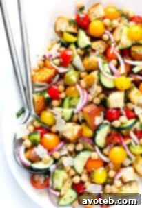 A vibrant bowl of Summer Panzanella salad with toasted bread, fresh tomatoes, cucumbers, and chickpeas.