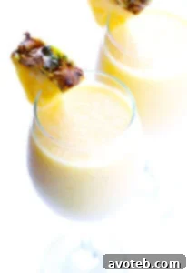 A vibrant Tropical Mimosa Smoothie in a glass, garnished with a pineapple wedge, perfect for brunch or a sunny day.
